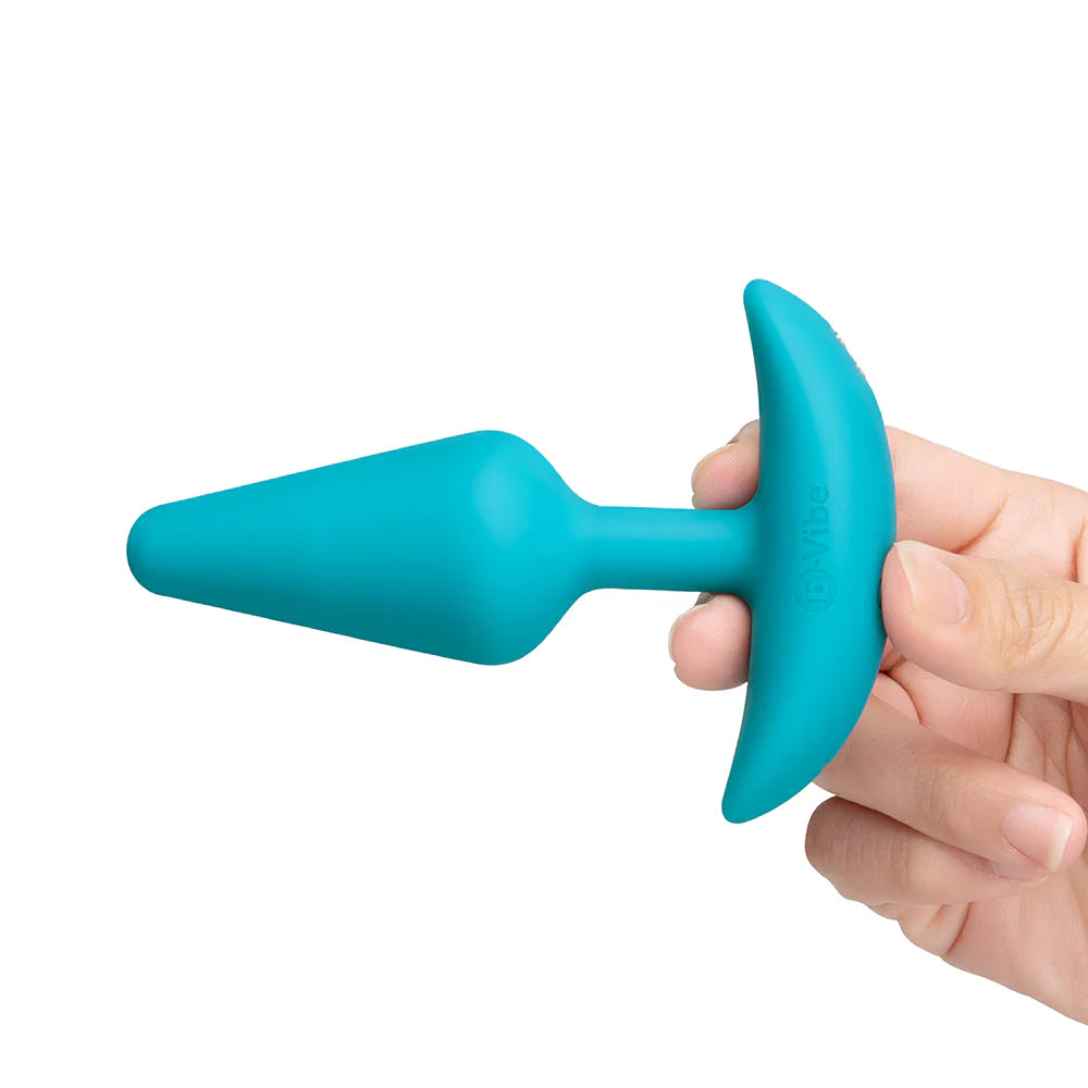Turquoise silicone butt plug held by a hand on a white background